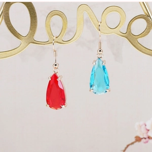 Close-up of red and blue faceted teardrop crystal pendants with golden claw settings