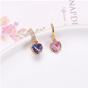 Macro detail of heart-shaped crystal pendants with gold lace edges on white ceramic