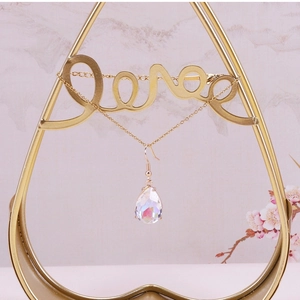 Macro detail of teardrop crystal earring with rainbow aurora effect on golden metal stand