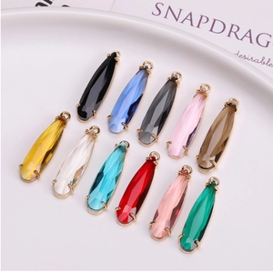 Macro shot of 11 colorful faceted teardrop crystal pendants with gold-plated metal base