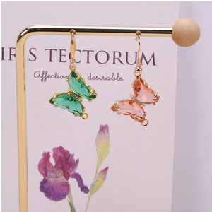 Detalle de los pendientes de mariposa de cristal con facetas esmeralda y rosa en soportes oro