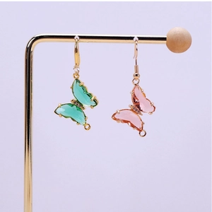 Detalle de colgantes de mariposa de cristal degradado con alas verde esmeralda y rosa