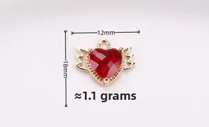 Detail view of a 12x18mm heart pendant with gold wings and a red crystal stone