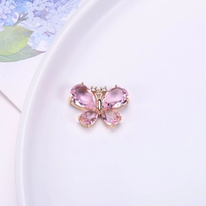 Detalle de colgante de mariposa de cristal rosa con base dorada para hacer joyería