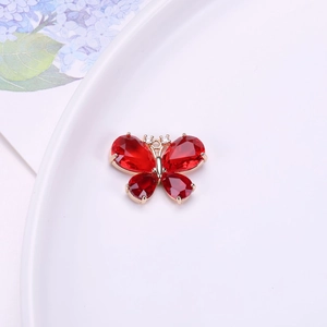 Detalle de colgante de mariposa de cristal rojo con marco de aleación de oro y circonitas