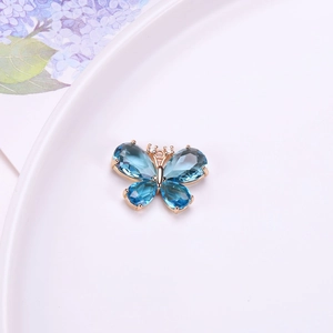 Vista detallada de un colgante de mariposa dorado con alas de cristal azul facetado