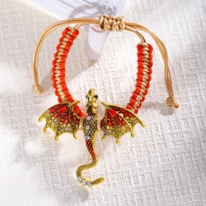 Detail van gouden drakenarmband met kleurrijke emaille vleugels en gevlochten koord