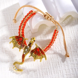 Macro detail of braided rope bracelet with golden dragon charm and red yellow enamel wings