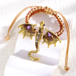 Detail of woven dragon bracelet with golden metal finish and purple stone accents
