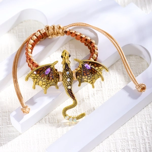 Detail van de gevlochten drakenarmband met goudkleurig email en paarse kristallen