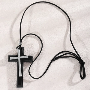 Detail of layered black wood and silver metal cross pendant on woven sweater chain