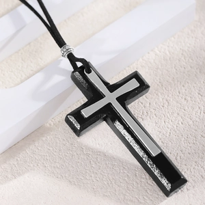 Detail of vintage black wooden cross pendant with silver metal inlay on sweater chain
