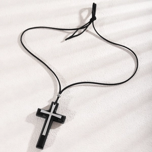 Close-up of black matte wooden cross pendant with silver inlay on adjustable rope