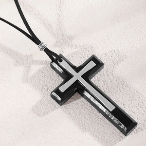 Macro view of vintage black cross pendant with silver carved bead on a black cord