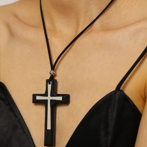 Detail of a vintage black wooden cross necklace with silver metal inlay on a model