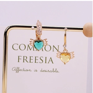 Detailed view of heart-shaped crystal earrings with golden wings and sparkling rhinestones