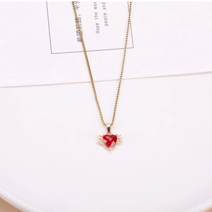 Detailed macro view of a gold-plated red heart crystal pendant with delicate golden wings