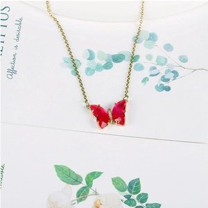 Detail of 14K gold butterfly pendant with red faceted crystal and sparkling rhinestones