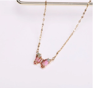 Detailopname van gouden vlinderhanger met roze en groen marmerpatroon op een standaard