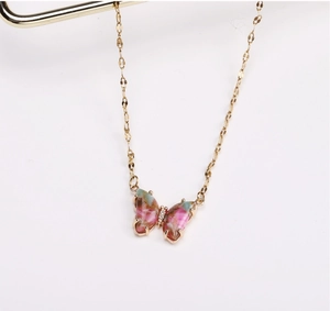 Macro detail van gouden vlinderhanger met roze en groene hars op een fijne O-ketting