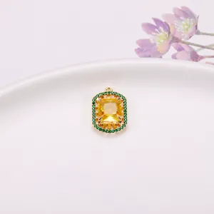 Elegante colgante rectangular de gema amarilla con halo verde, acabado oro 15x21mm
