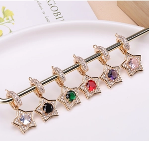 Close-up of gold-plated star pendants with colorful center stones and pavé zircon settings