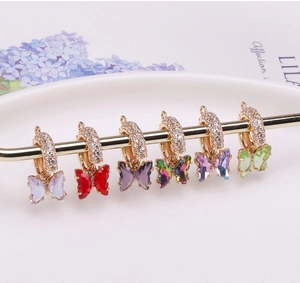 Détail de breloques papillons en cristal coloré avec montures dorées et accents de zircon