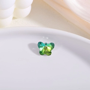 Macro shot of faceted crystal butterfly pendant with vibrant green and yellow gradient
