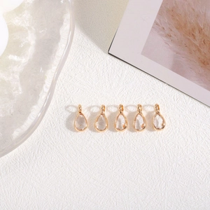 Vijf vergulde waterdruppel hangers voor DIY sieraden maken op een witte achtergrond