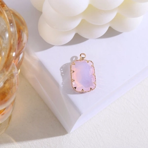 Detalle de colgante de cristal rosa rectangular con engaste de garras sobre cubo blanco