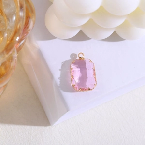 Vista detallada del colgante de cristal rosa rectangular con engaste de garras doradas