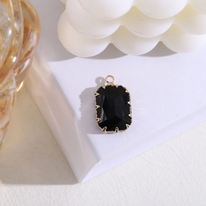 Detalle de un colgante rectangular de piedra negra con engaste de garras chapado en oro