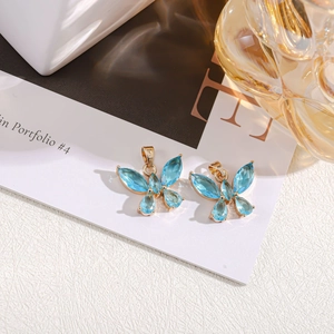 Detailed close-up of blue crystal butterfly charms with gold plating for jewelry making