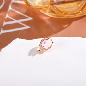 Dettaglio ravvicinato dell'orecchino con cristallo rosa ovale e montatura dorata