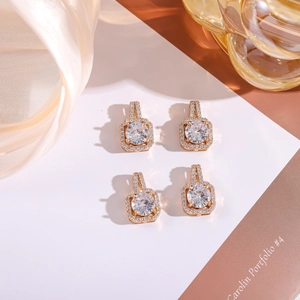 Detailed macro view of four square gold-plated stud earrings with sparkling round zircons