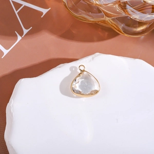 Detail of a pear-shaped crystal pendant with gold plating on a white stone pedestal