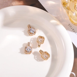 Detailed view of four golden square halo pendants with round white zircon on a white plate