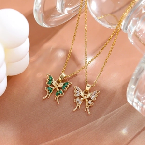 Golden butterfly necklace with green and clear zircon pendants on champagne satin background