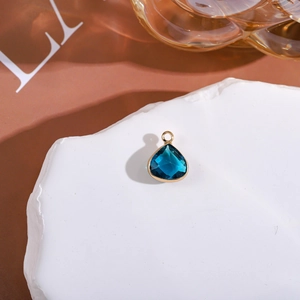 Close-up of faceted dark blue teardrop crystal pendant with gold metal edge detailing