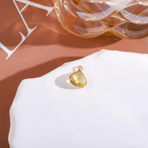 Close-up of a teardrop yellow crystal pendant with gold frame on a stone tray