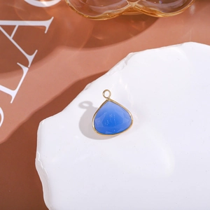 Macro detail of blue teardrop crystal pendant with gold rim on white rock base