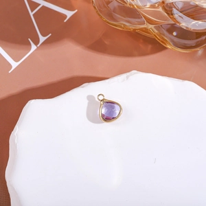 Macro detail of purple water drop gemstone pendant with golden metal frame and ring