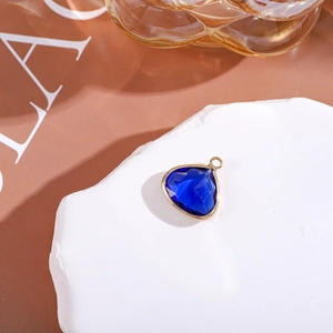 Macro shot of triangle dark blue crystal pendant with gold rim on white stone base