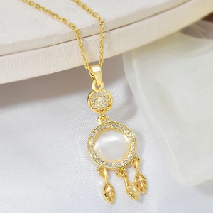 Macro shot of dreamcatcher necklace with white cat eye stone and gold leaf charms