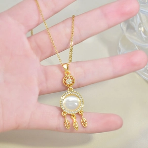 Detail of a gold dreamcatcher necklace with a round opal stone and leaf tassels