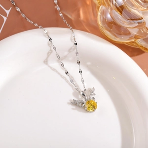 Close-up of deer antler necklace with yellow gemstone pendant on white ceramic plate