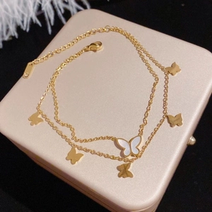 Double-layered gold butterfly anklet with shell inlay on pink jewelry box background