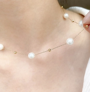 Detail view of dainty pearl and gold bead necklace worn on neck highlighting elegant clavicle