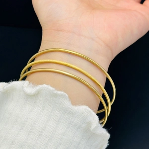 Three-piece minimalist gold bangle set featuring polished and frosted finishes for women