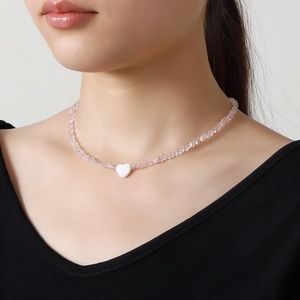 Pink crystal beaded necklace with heart pearl pendant on a model wearing V-neck top